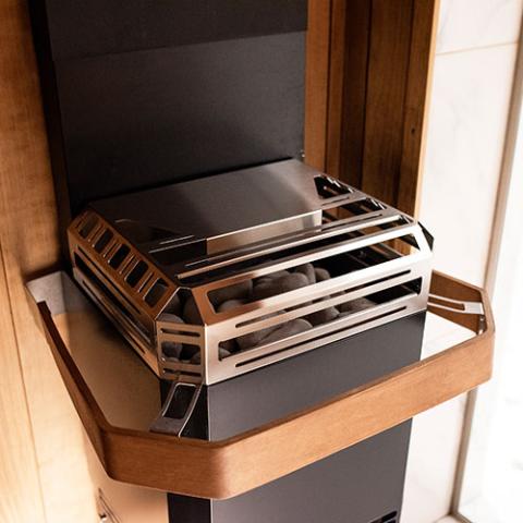 Saunum AIR L 13 black sauna heater with stainless steel accents and wooden shelf, designed for optimal heat distribution.