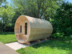 6-person Eastern White Cedar barrel sauna with porch, made by Dundalk, features natural wood finish and spacious design.